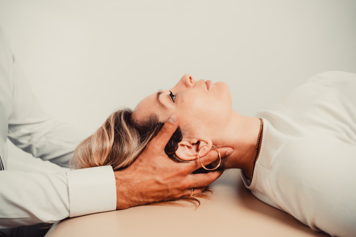 Nasłuch osteopatyczny — dłoń terapeuty pod głową pacjentki